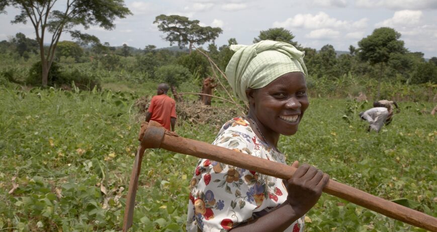 Ugandan farmer and group animator holding a hoe in a communal garden