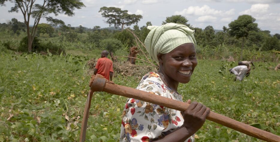 Ugandan farmer and group animator holding a hoe in a communal garden