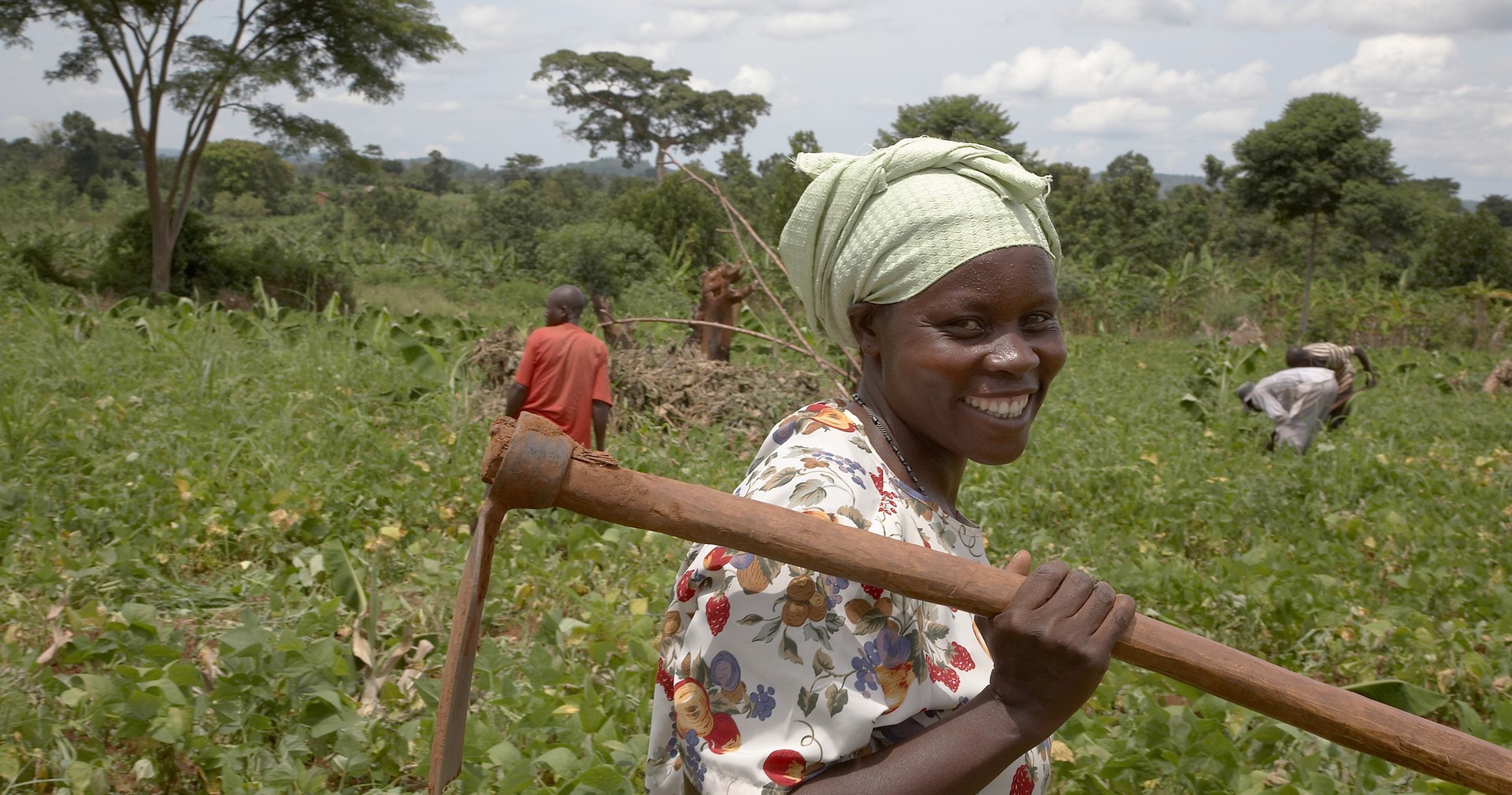 Ugandan farmer and group animator holding a hoe in a communal garden